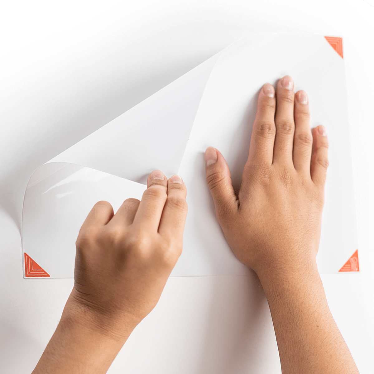 person installing the peel-and-stick whiteboard on a wall