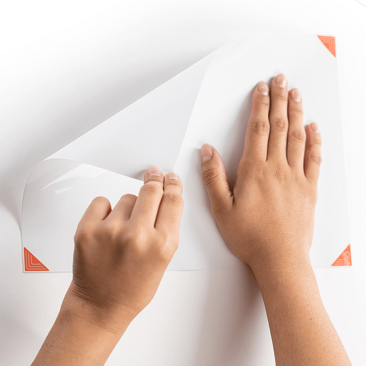 person installing the peel-and-stick whiteboard on a wall